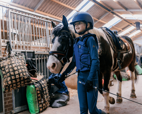 Een jeugdlid van Ruitervereniging Rozenburg loopt trots met haar paard en het nieuwe zadel!