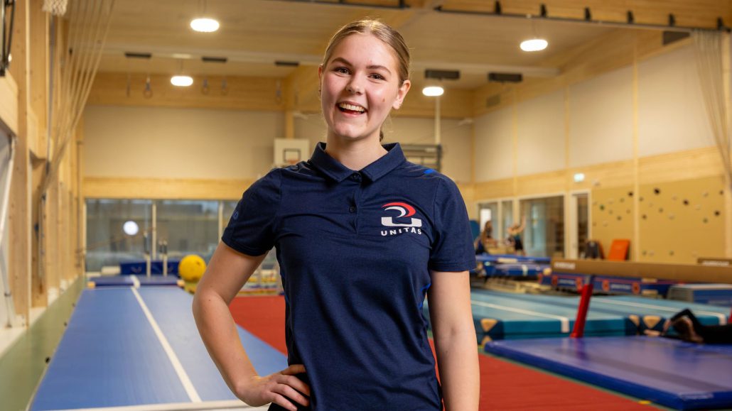 Met een grote glimlach staat trainer Quinty op de foto bij gymnastiekvereniging Unitas