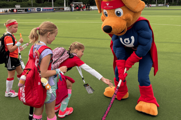 Jeugdleden leggen Cluppie uit hoe hij het beste kan hockeyen